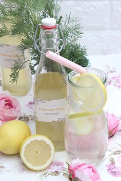 a bottle of lemonade next to sliced lemons on a table with pink flowers