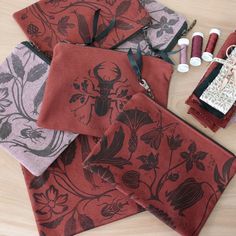 four pieces of red and grey fabric with various sewing supplies on top of each other