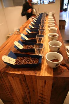 a long wooden table with cups and bowls on it