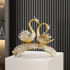 two golden swans sitting on top of a white box