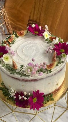 a white cake with flowers on top sitting on a gold plate