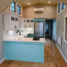 a kitchen with white cabinets and blue counter tops in a tiny cabin style home on wheels