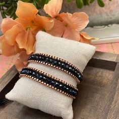 two bracelets sitting on top of a pillow next to flowers