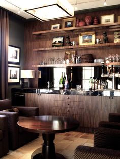 a room with some chairs and pictures on the wall next to a table in front of a bar