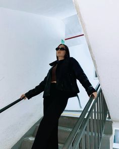 a woman is standing on the stairs with her arms spread out and holding an umbrella