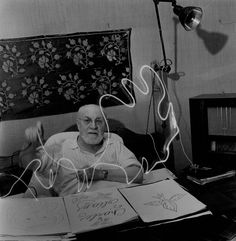 an old man is sitting at his desk in front of some books with writing on them