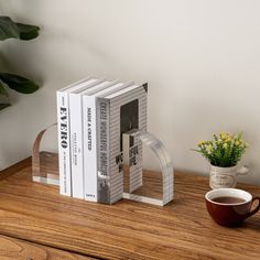 a stack of books sitting on top of a wooden table next to a coffee cup