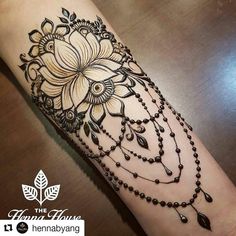 a woman's arm with a flower and beads tattoo on the wrist, while she is wearing a black beaded bracelet