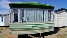 a green and white trailer parked next to other trailers