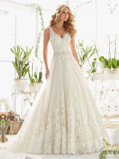 a woman in a wedding dress standing next to plants