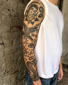 a man with a tattoo on his arm standing next to a brick wall