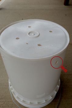 a white plastic container with a red marker on the bottom and an orange circle at the top