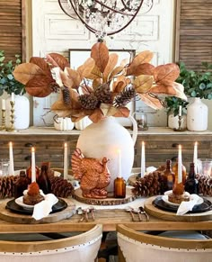 a dining room table set for thanksgiving with candles, plates and turkeys on it