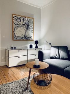 a living room filled with furniture and a painting hanging on the wall over a coffee table