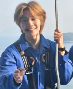 a woman in blue is holding onto a rope and smiling at the camera while standing on a boat