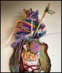 a decorative mask with feathers and other things on it's face, hanging from the wall