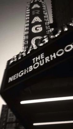 the marquee for the neighborhood theatre is lit up in black and white photo