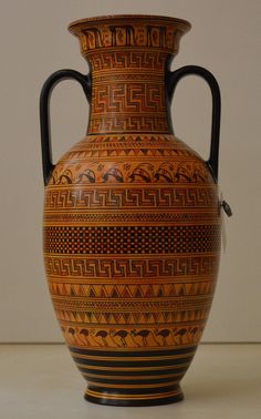 a large vase with designs on it sitting on a table next to a white wall