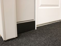 an open white door with black trim on the floor and carpet in front of it