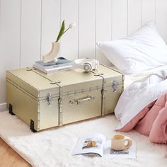 an open suitcase sitting on top of a white rug next to a book and cup