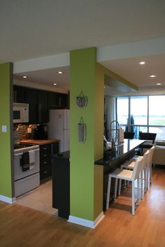 an open kitchen and living room area with wood floors, green walls, and white appliances