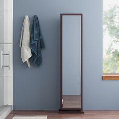 a mirror and towel rack in a bathroom next to a bathtub with blue walls