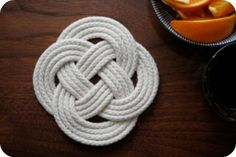 a white rope sitting on top of a wooden table next to a bowl of fruit