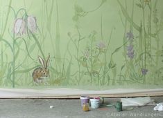 a rabbit sitting in the middle of a room with flowers painted on it's walls