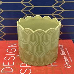 a green vase sitting on top of a red book