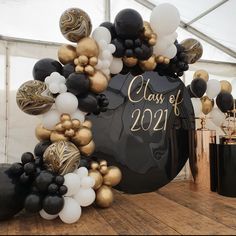 black and gold balloon arch with class of 2021 sign surrounded by balloons in the background