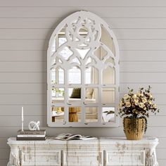 a white dresser with a mirror on top of it next to a vase filled with flowers