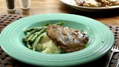 a green plate topped with meat and mashed potatoes on top of a wooden table