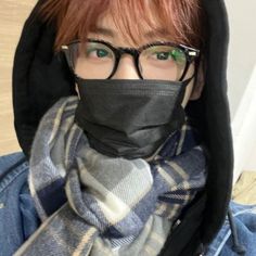 a person wearing glasses and a black mask with a scarf around their neck is looking at the camera