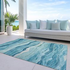 a living room with a couch and rug on the floor next to an ocean view