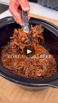 a person is spooning some food into a slow cooker with the words korean bbq beef on it