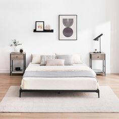 a bedroom with white walls and wood flooring has a bed, nightstands, and pictures on the wall