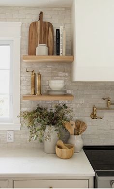 a kitchen with white counter tops and open shelving above the stove, along with wooden utensils