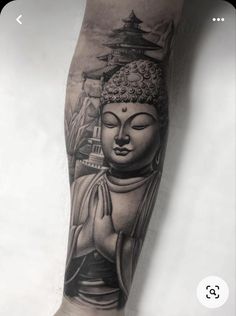 a person with a tattoo on their arm and leg is holding a buddha statue in front of