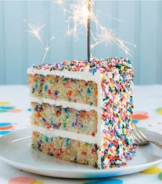 a slice of birthday cake with sprinkles and a sparkler on top