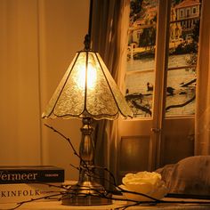 a lamp sitting on top of a table next to a book