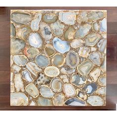 an abstract painting made out of different types of rocks and stones on a wood floor