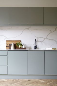 a kitchen with grey cabinets and white counter tops