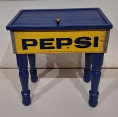 a small blue and yellow table with the word pepsi on it's bottom shelf