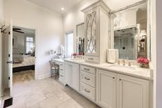 a large bathroom with white cabinets and marble counter tops