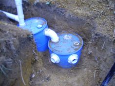 two blue plastic barrels sitting in the dirt