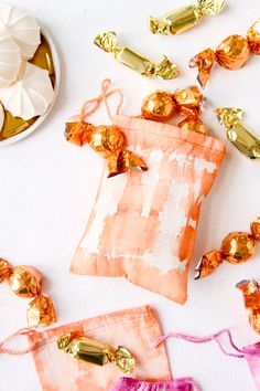 candy bags with gold foiled candies in them on a white surface next to spoons