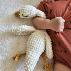 a small child laying on top of a bed with a knitted sheep toy next to it