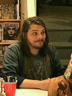 a man with long hair sitting at a table