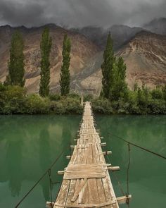 a long wooden bridge over water with mountains in the background