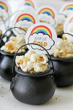 small pots filled with popcorn sitting on top of a white table covered in rainbows